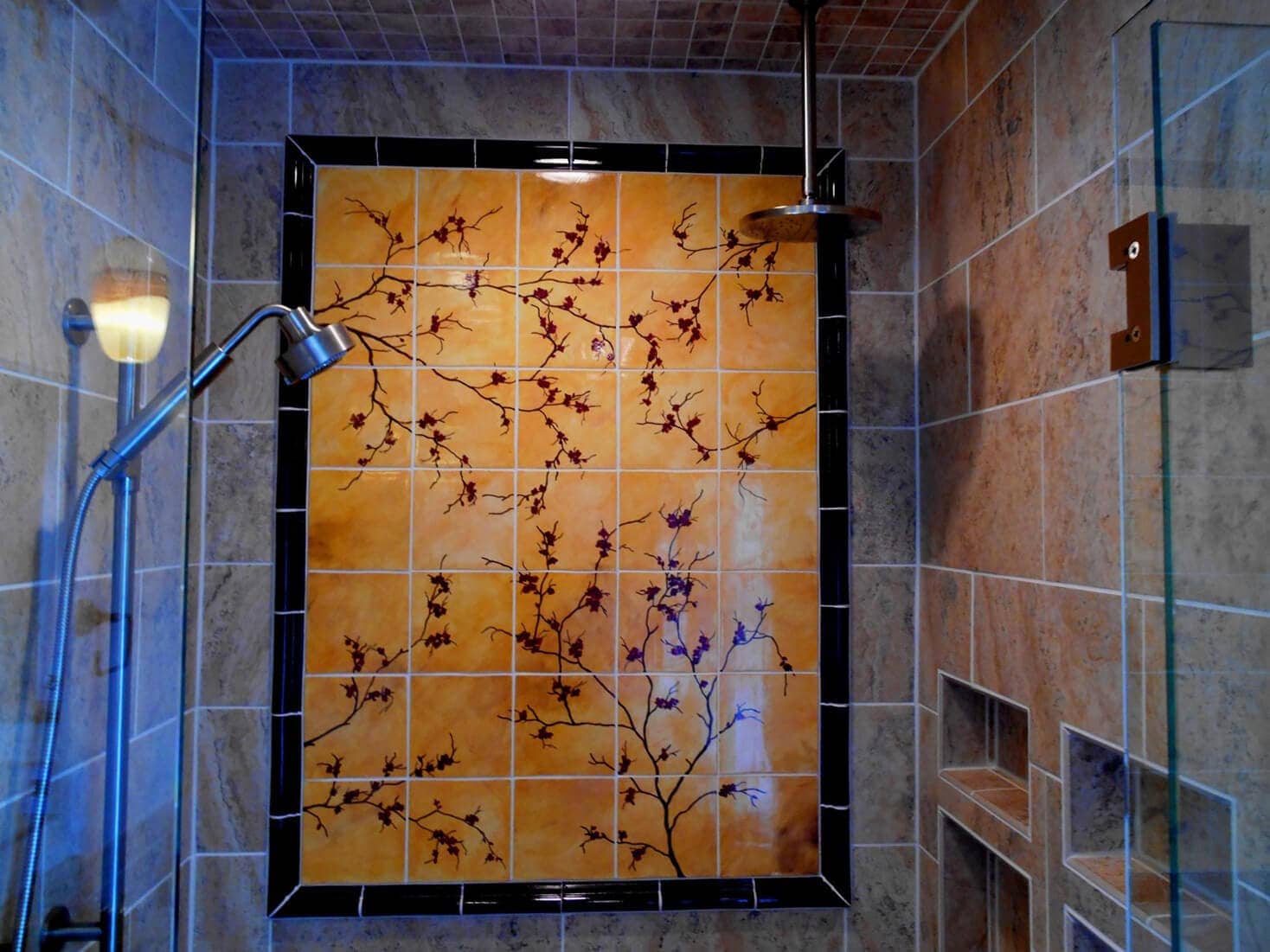Click to Expand our Shower Tile Ideas Gallery 🔍 Shower tile designs with hand-painted floral ceramic mural feature wall framed in black trim and stone-look surrounding tiles