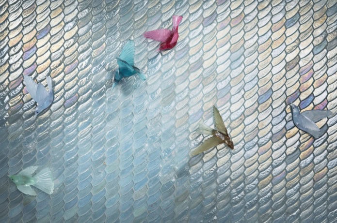 Iridescent blue mosaic tiles with origami cranes on top
