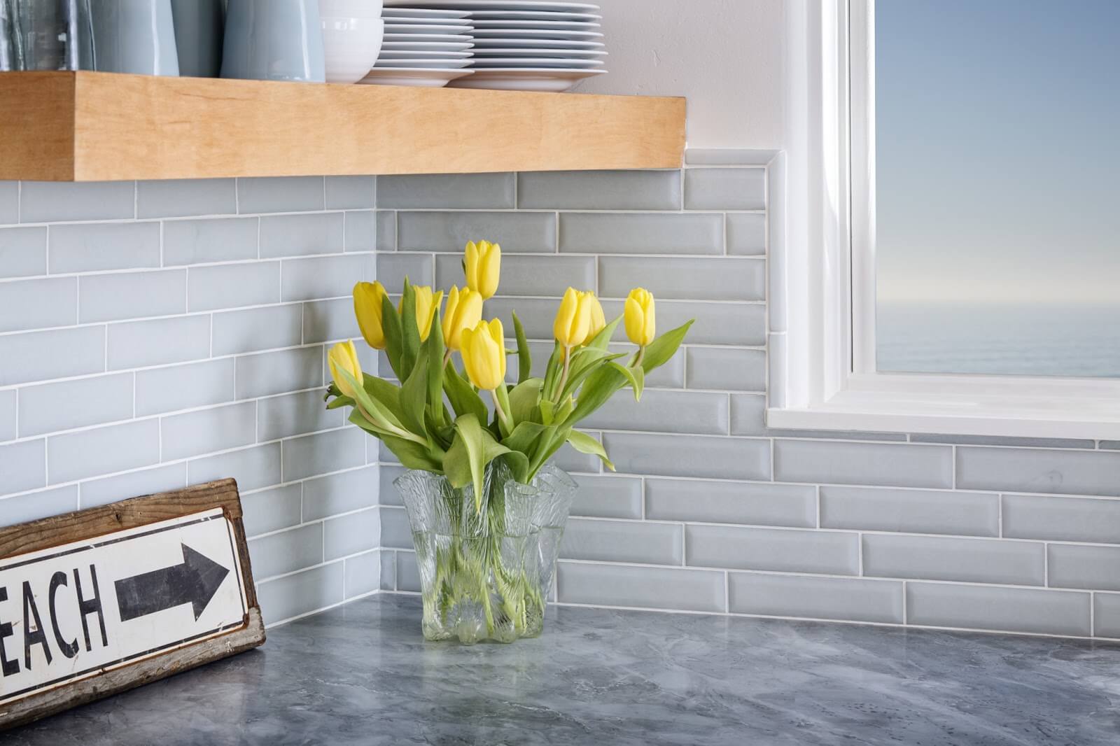 Yellow tulips on a kitchen counter with baby blue subway tile backsplash