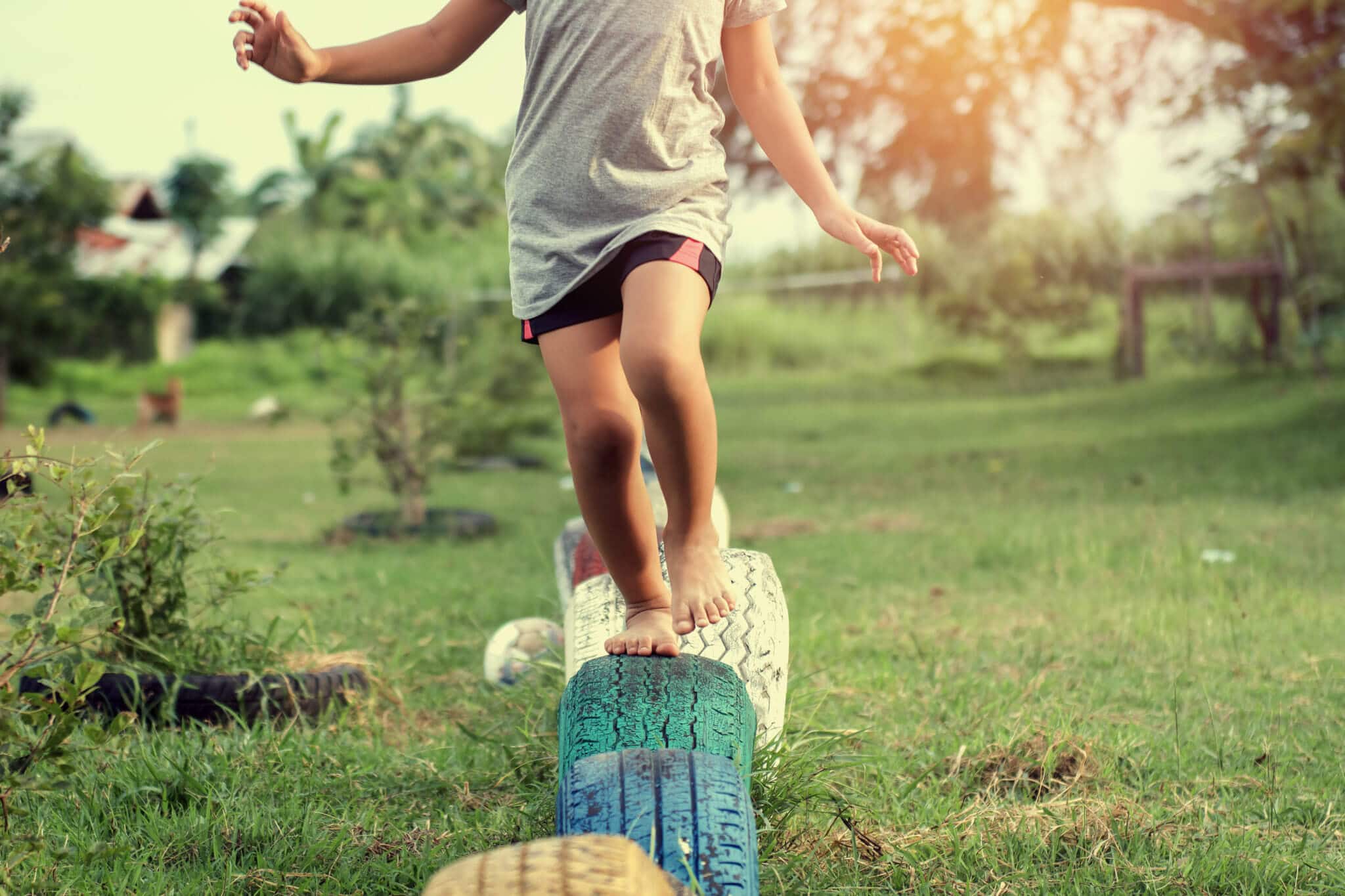 A child runs barefoot on toy tires in a playground