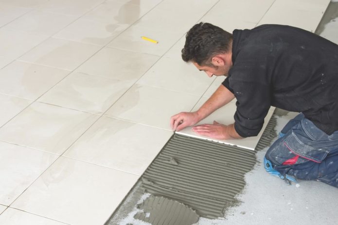 A man installing floor tile