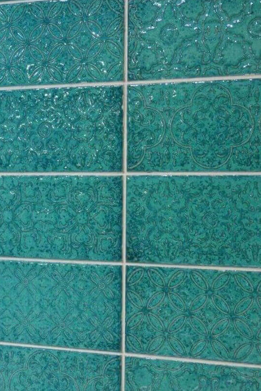 Turquoise tile with floral designs and a textured, high-floss surface