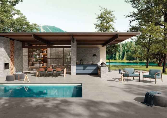 The back patio area of a modern house showcasing a pool with gray tile surrounding it.