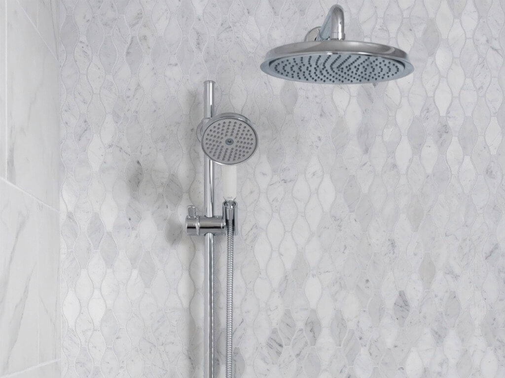 White shower mosaic tiles in arabesque-like shapes that create vertical lines
