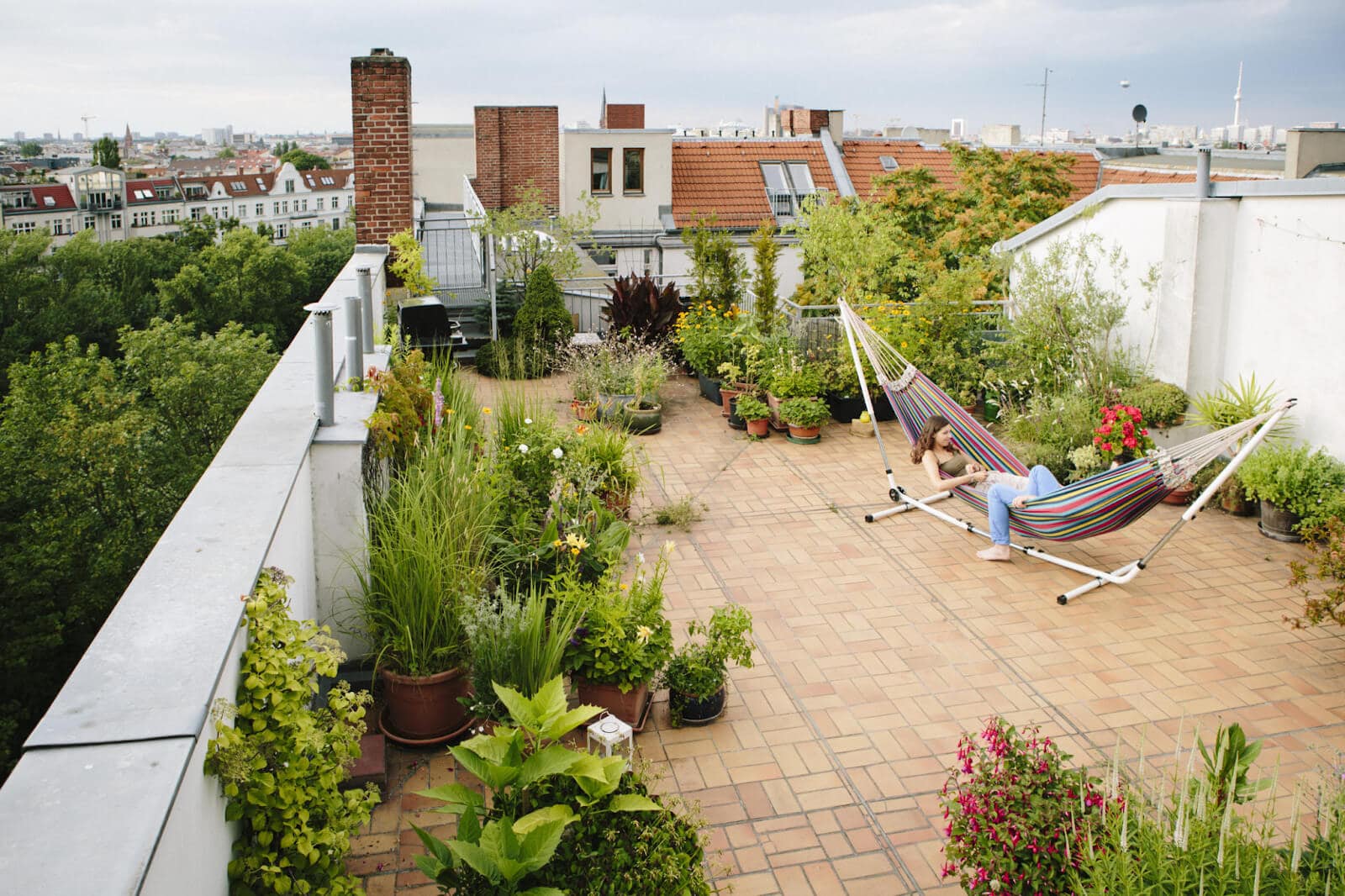 two people on a hammock in an outdoor patio full of plants and ceramic tile flooring