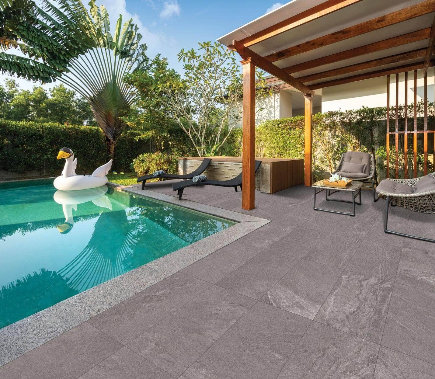 pool area with seating area and gray ceramic tile flooring for a resort-look