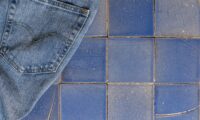Denim jeans placed atop different tones of blue tiles