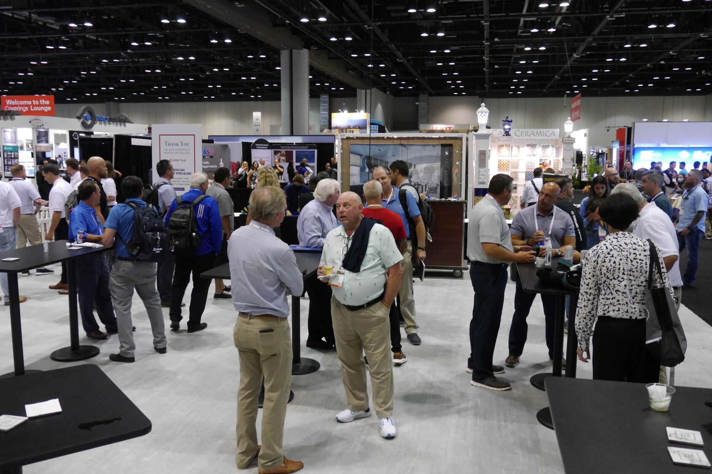 A group of attendees mingling during a happy hour on the Coverings conference show floor. 