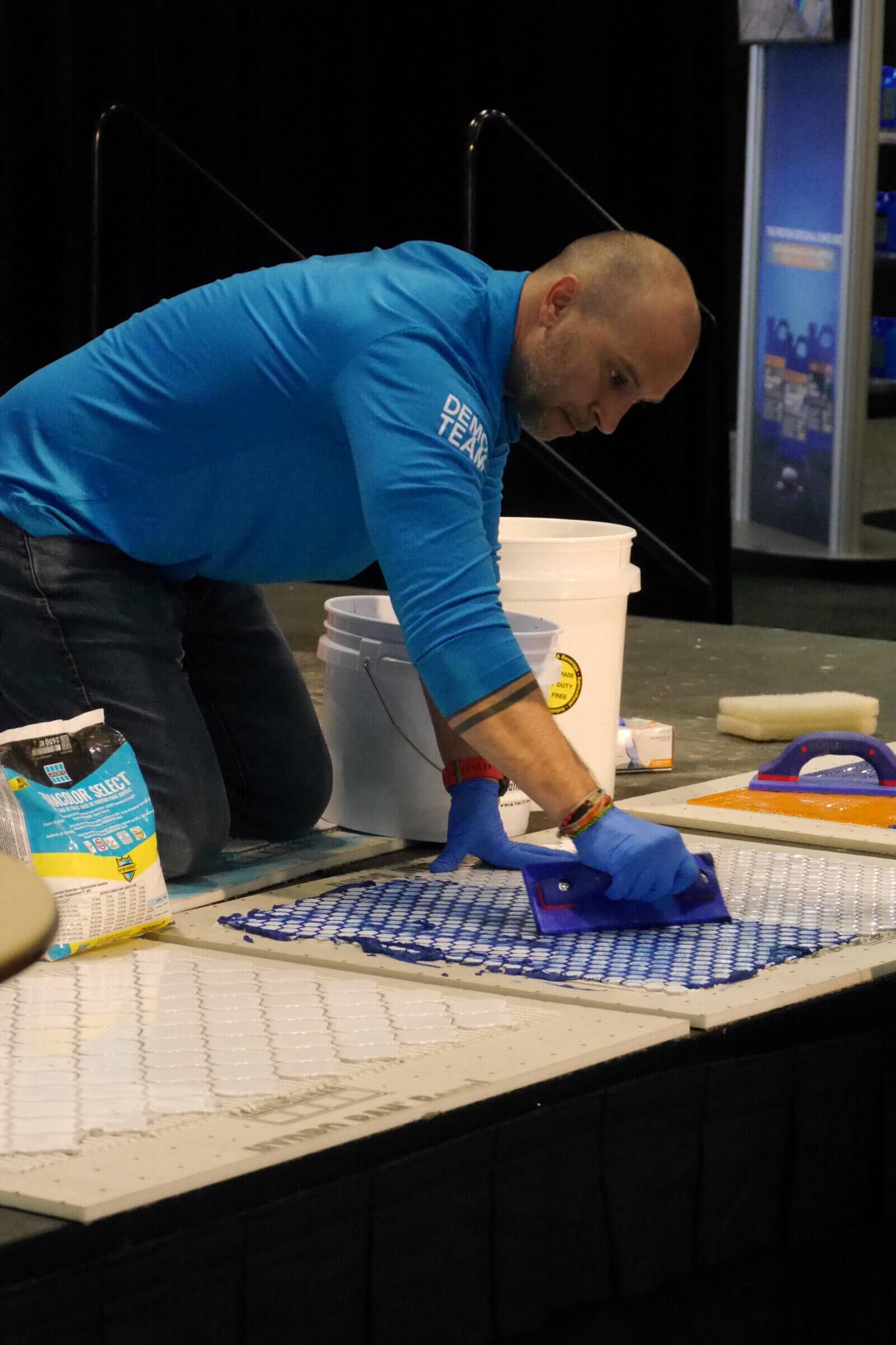 A man from a demo team at the Coverings conference applying a treatment to tiles. 
