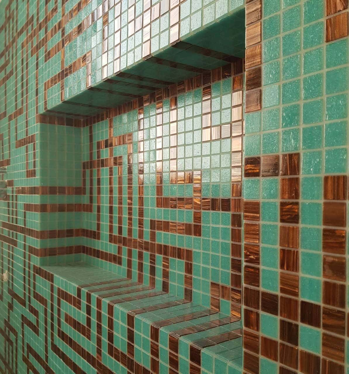 Mosaic tile pattern of tiger’s eye and jade-look tiles flows from the shower walls into the niche, blending ultra-modern design with neo Greco-Roman inspiration