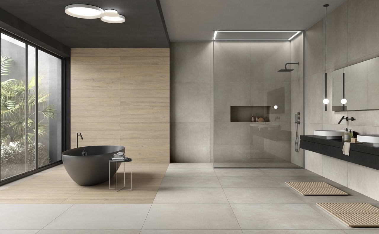 Deep horizontal shower niche with large-format gray tile, matching matte gray walls, contrasting with the curved bathtub and fixtures