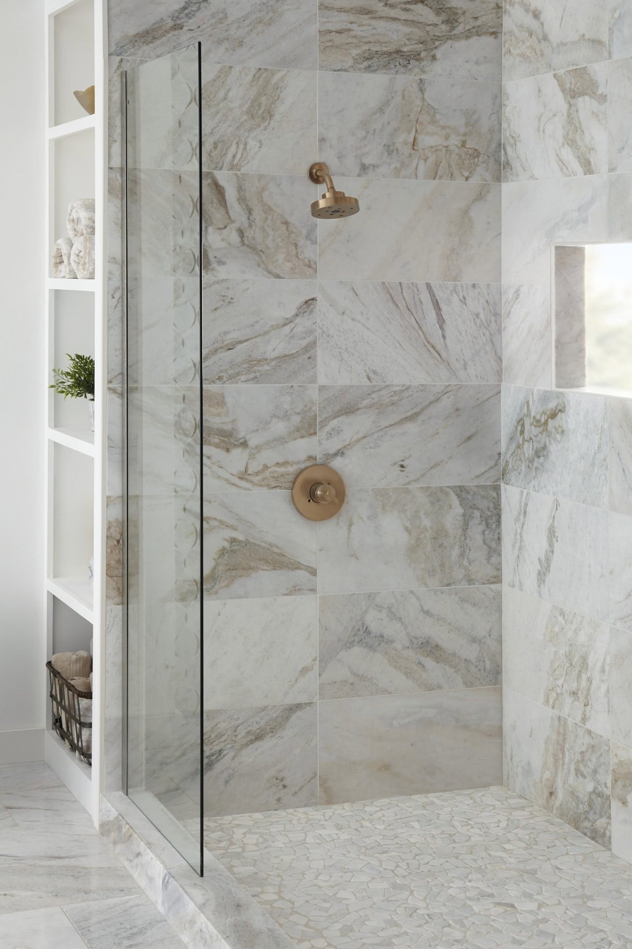 White marble-look tile frames this shower niche and window, with natural light highlighting the mosaic tile floor for a fresh, airy feel