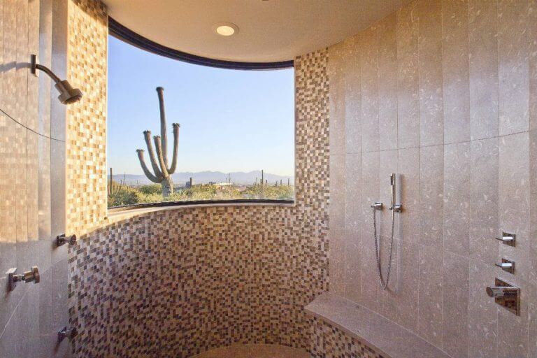 Curved built-in shower bench with a beige stone-look tile seat and natural-toned mosaic base