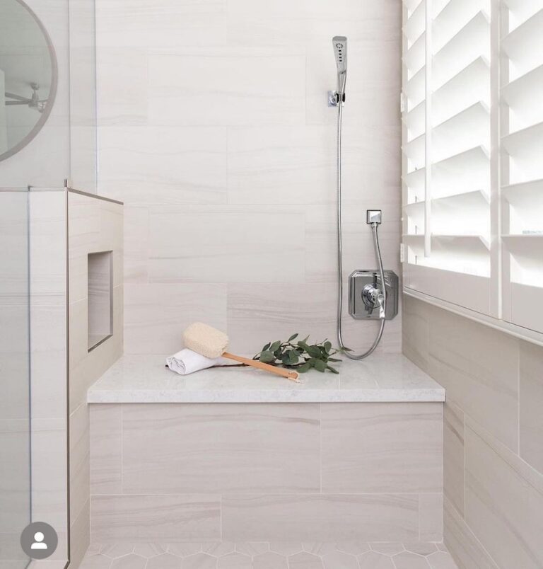 Accessible white and beige tiled shower bench with an adjacent recessed niche