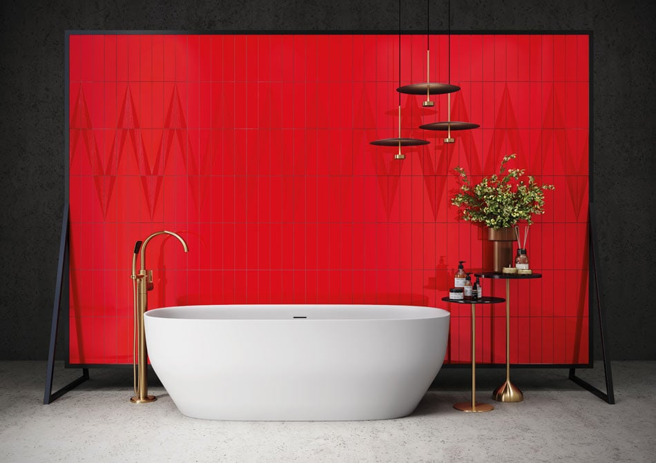White freestanding bathtub with a bright colorful wall tile, a red ceramic tile feature behind it