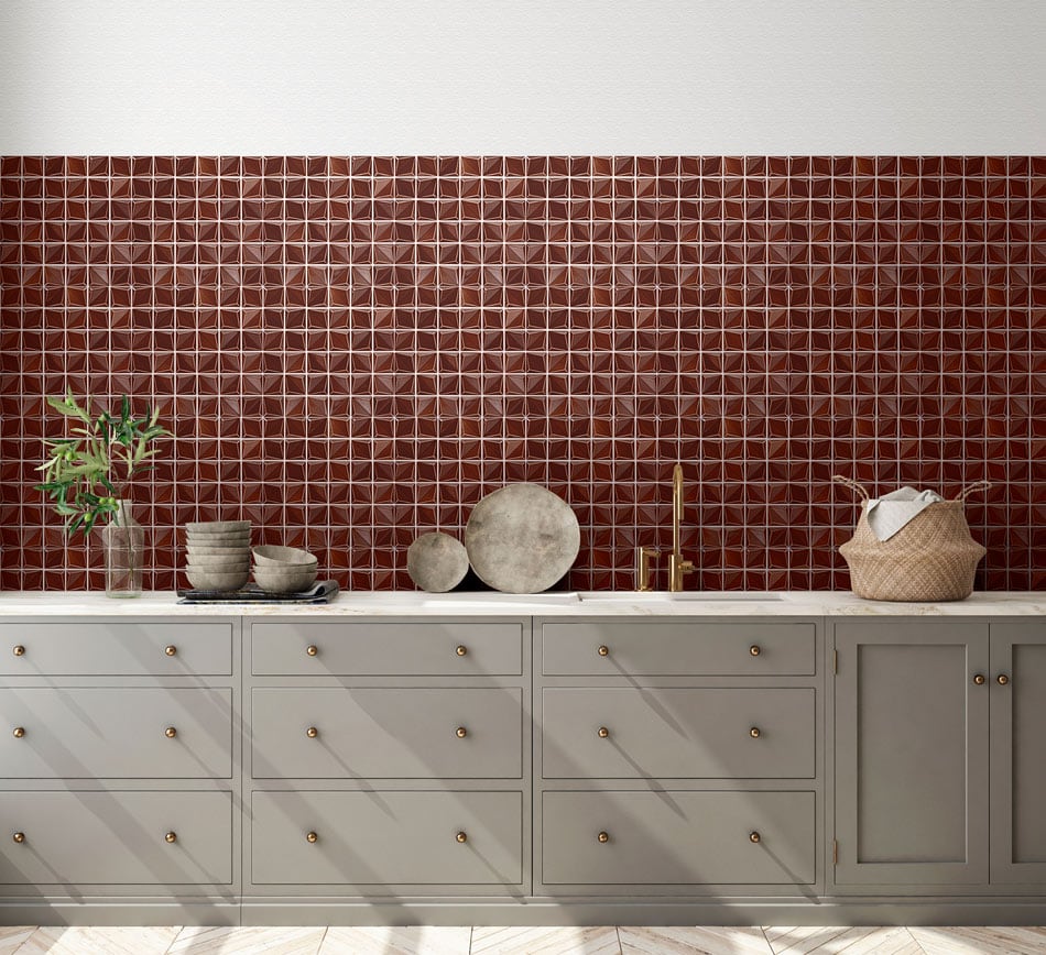 Kitchen backsplash of glossy dark cherry-red geometric tiles above grey cabinetry