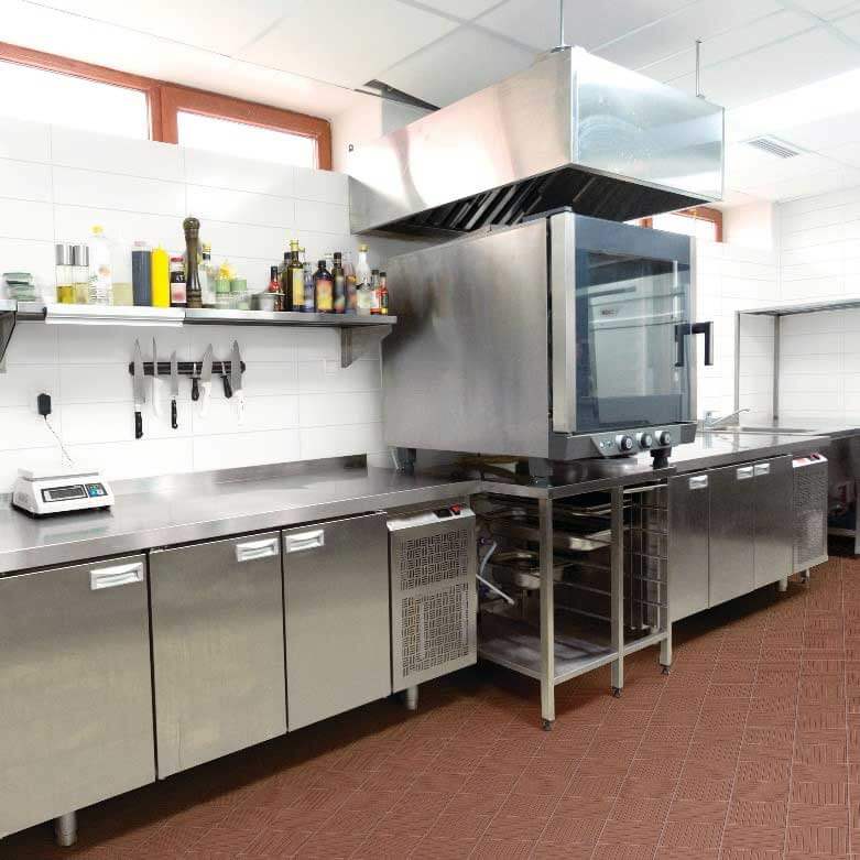 Commercial kitchen floor and wall tiles with brown textured ceramic floor tile and white subway wall tile in a professional restaurant kitchen