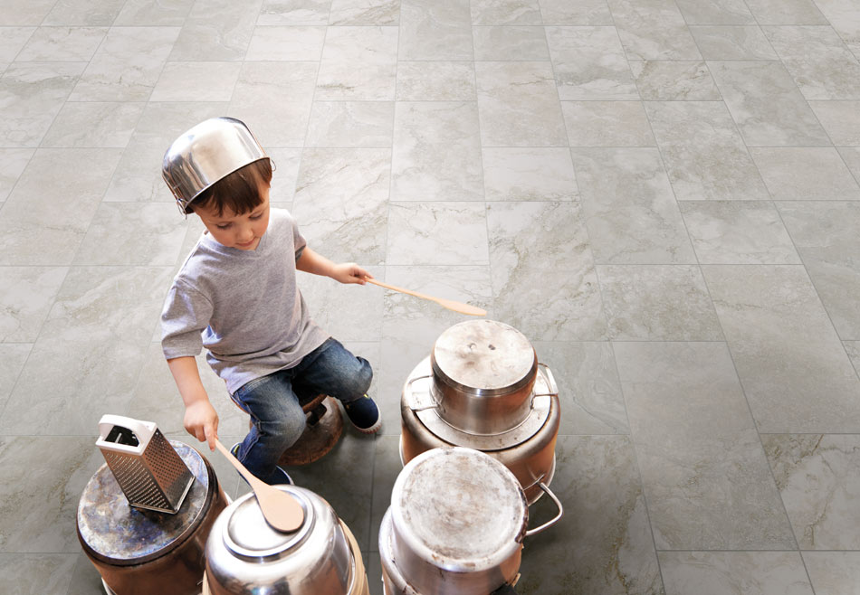 Swirling gray marble-look floor tile in a spacious children’s playroom with kid playing