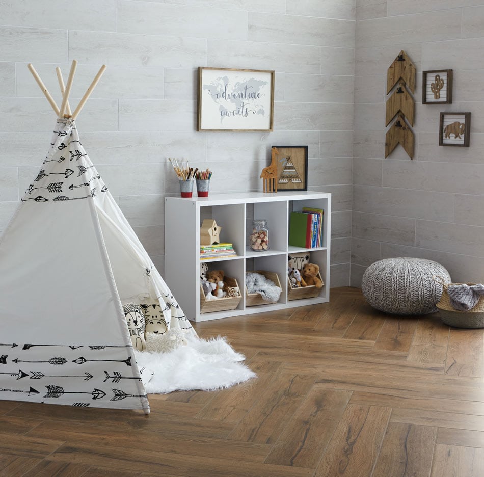 Children’s playroom with teepee tent featuring chocolate wood-look floor tile in herringbone layout and stone-look subway wall tile
