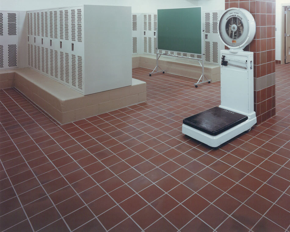 Locker room with deep terracotta-look ceramic quarry tile and white grout in a grid pattern