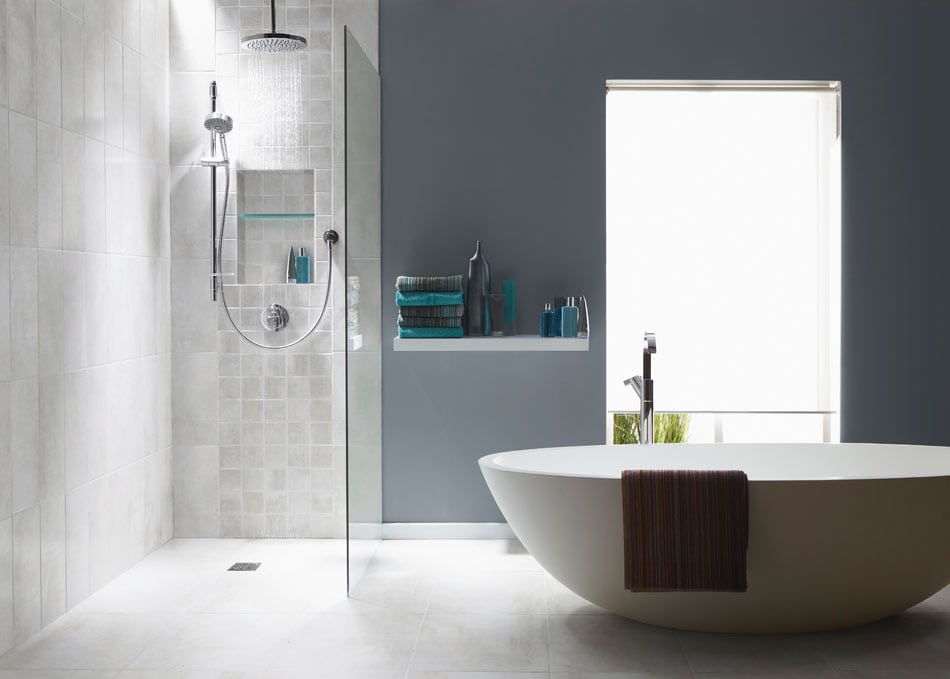 Open-concept bathroom with undulated square ivory tile wall, vertical grid tile in the shower, and a tub