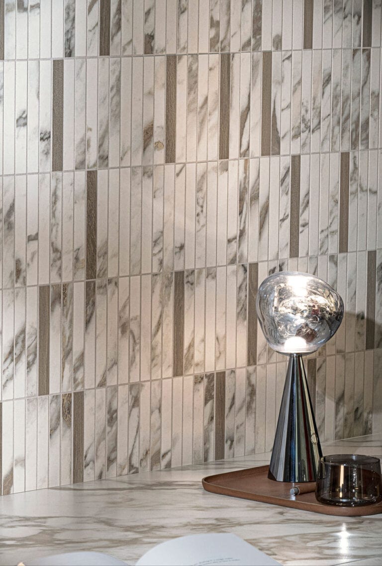 Random tile design with thin ivory marble-look tiles and chocolate wood-look accent strips on wall
