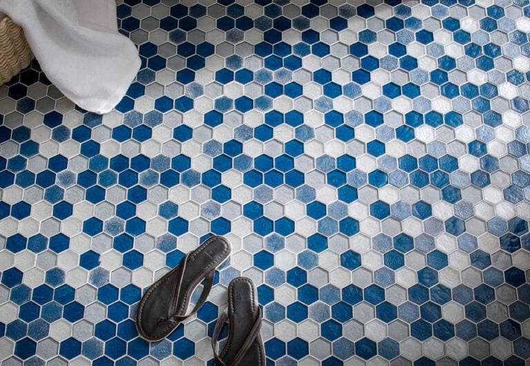 Random tile pattern with blue, gray and white hexagon mosaic tiles on bathroom floor