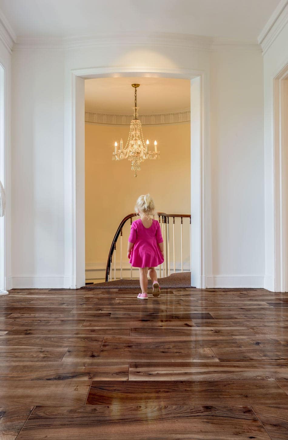 Young girl in pink dress walking on glossy cherrywood-look floor tile in a bright playroom