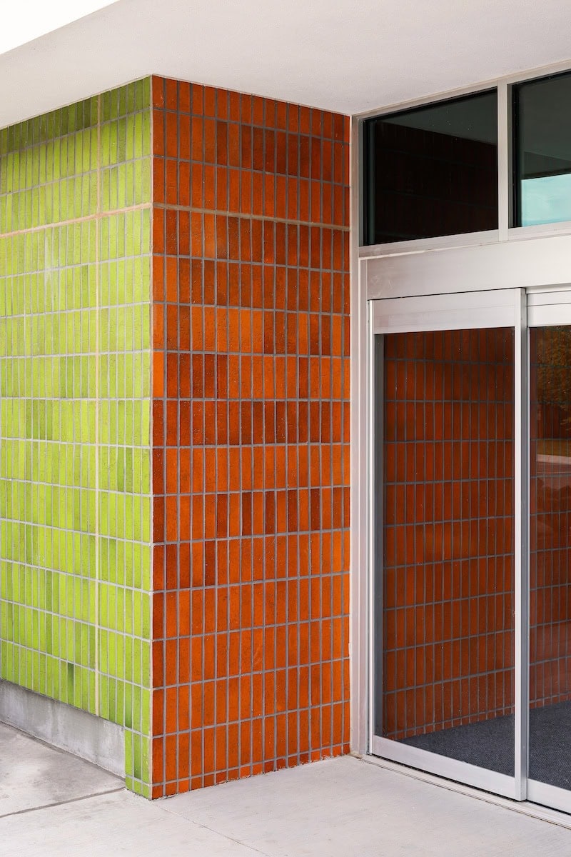 Library exterior with red-orange brick-look wall tile and avocado-green tile arranged in a geometric pattern