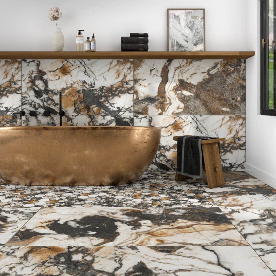 Elegant bathroom design with large ivory porcelain tiles swirling with gold and grey veins, and a hex mosaic surrounding a metallic bathtub