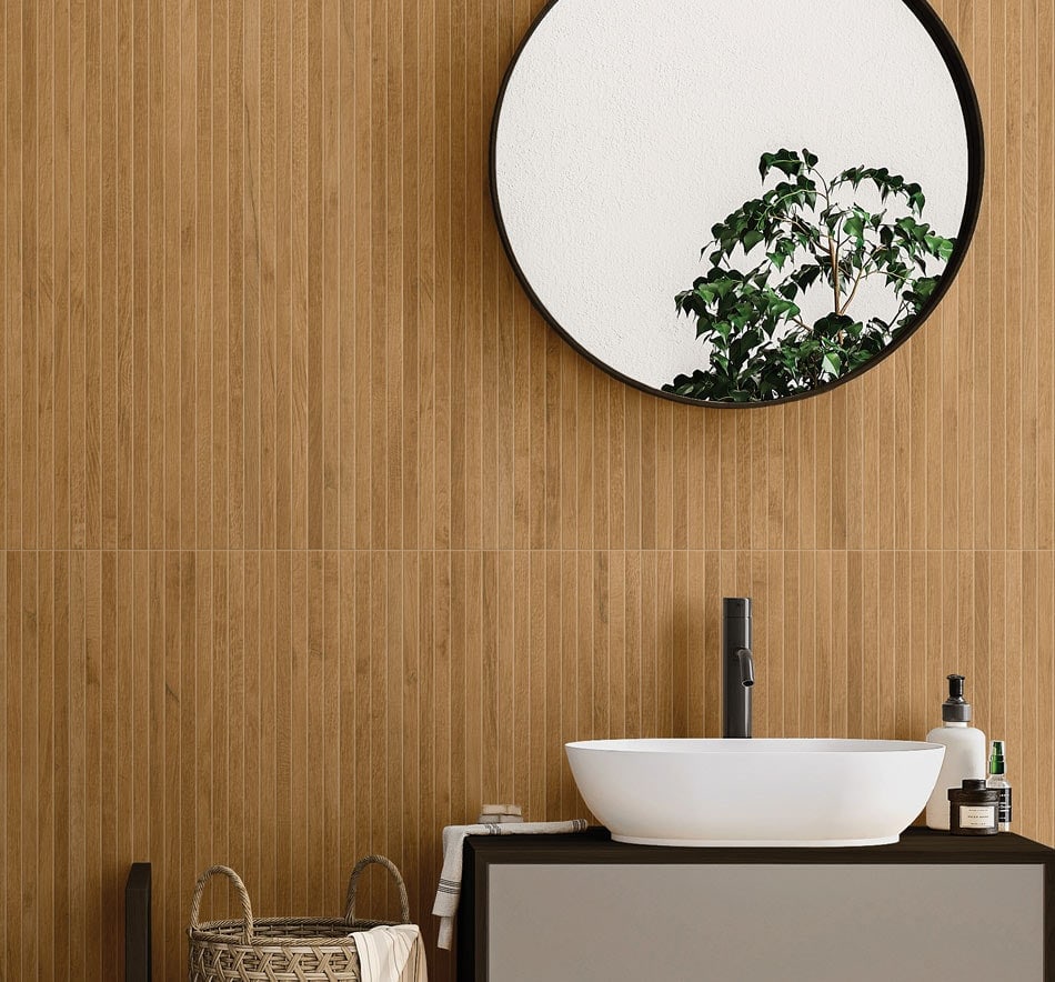 Elegant bathroom design featuring golden-brown wood-effect ceramic tiles and a round mirror reflecting greenery