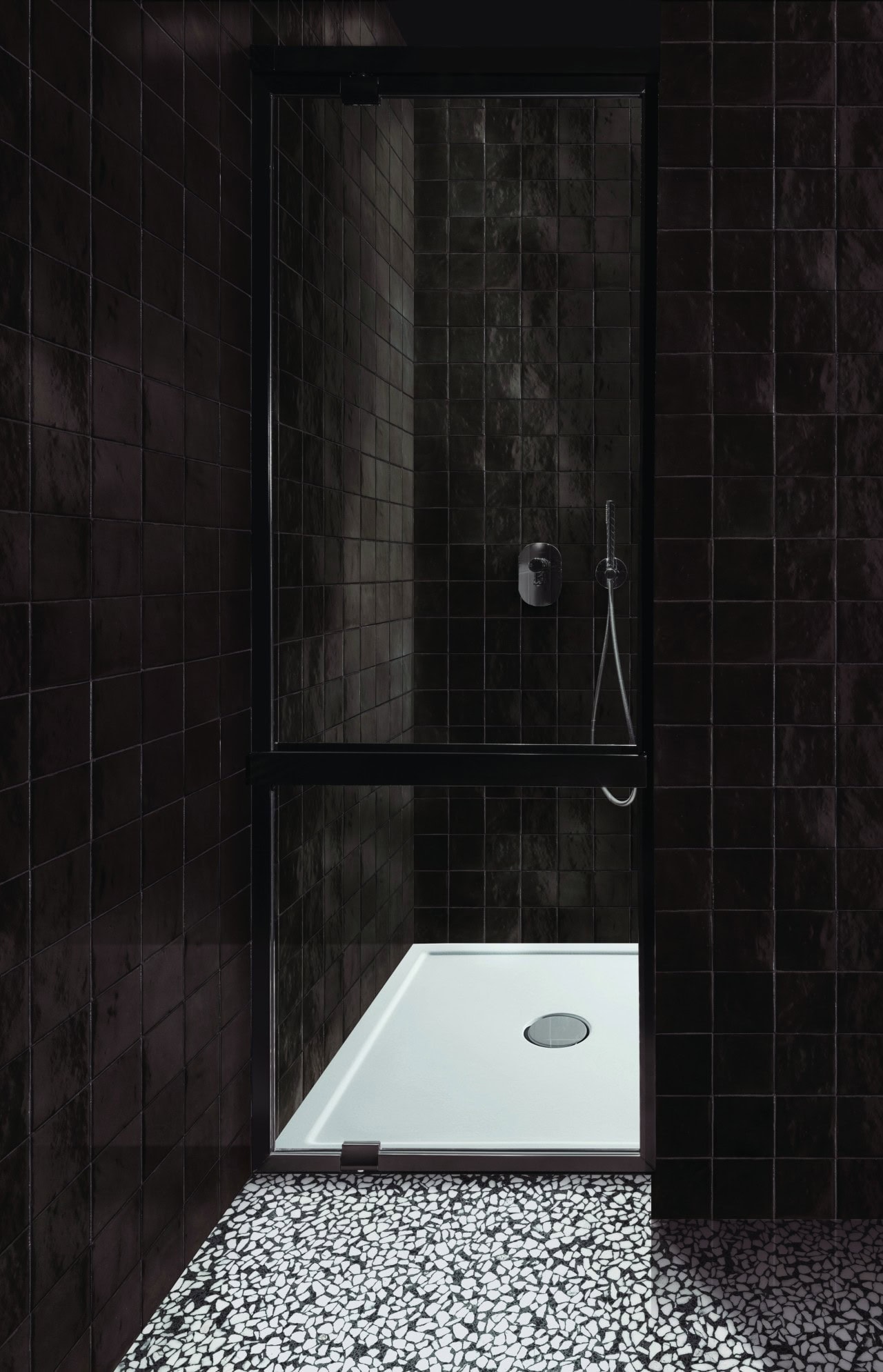 Steam shower with dark chocolate tiles framed in bold black, creating a decadent and moody atmosphere for relaxation