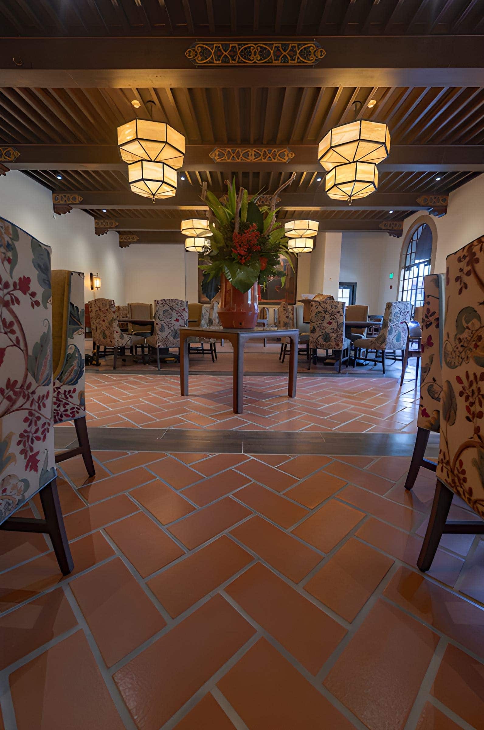 Dining hall with terracotta-look floor tiles, wood-look tile framing a herringbone layout
