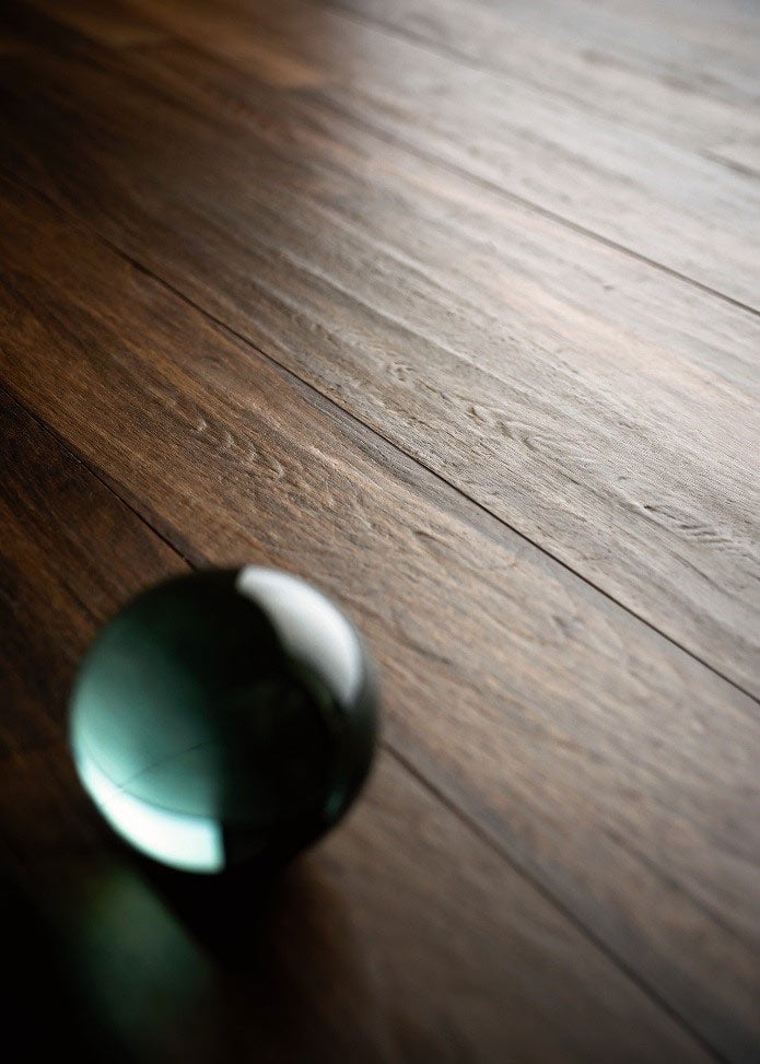 Close-up of wood grain ceramic tile with green marble detailing, showcasing 2025 textural realism tile trends